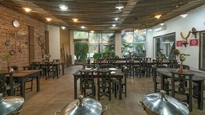 A restaurant with brick walls, wooden tables, and metal serving dishes. - Delight Stay Resort Dhikuli - Corbett (Ramnagar)