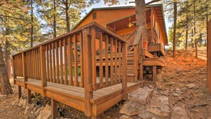 Eine Holzterrasse mit Geländer, eine Treppe, die zu einer Hütte führt, und felsiger Untergrund.