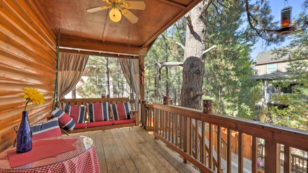 Eine Holzterrasse mit Deckenventilator, einem Tisch mit kariertem Tischläufer und einer Couch mit gestreiften Kissen.