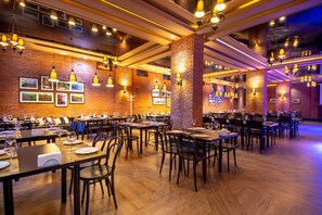 A spacious restaurant with brick walls, wooden tables, and hanging pendant lights.