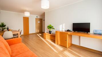 Una sala de estar moderna con una mesa de centro de madera, sofá naranja y un televisor sobre un mueble de madera.