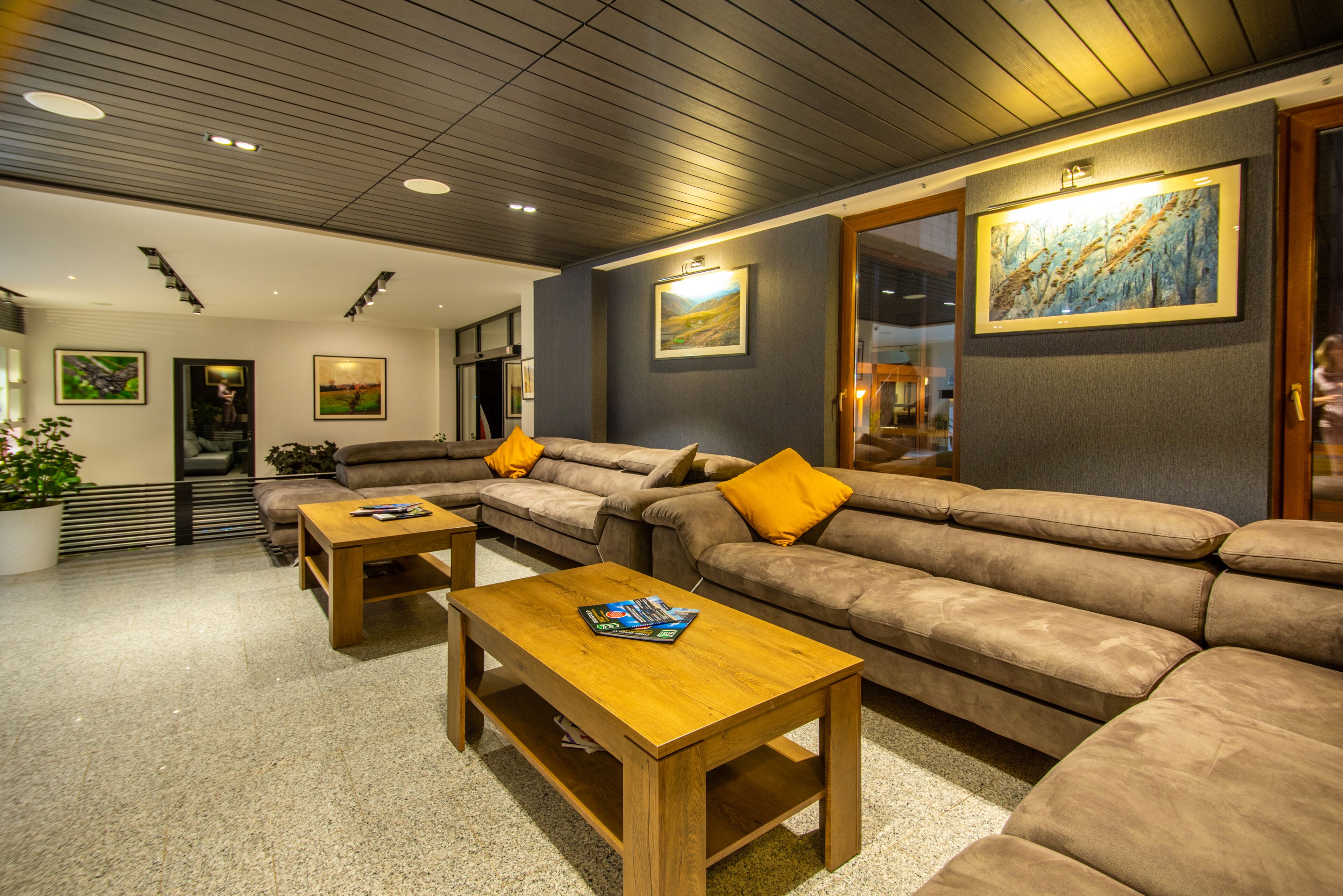 A modern living room with a sectional sofa, wooden coffee table, and artwork on the walls.