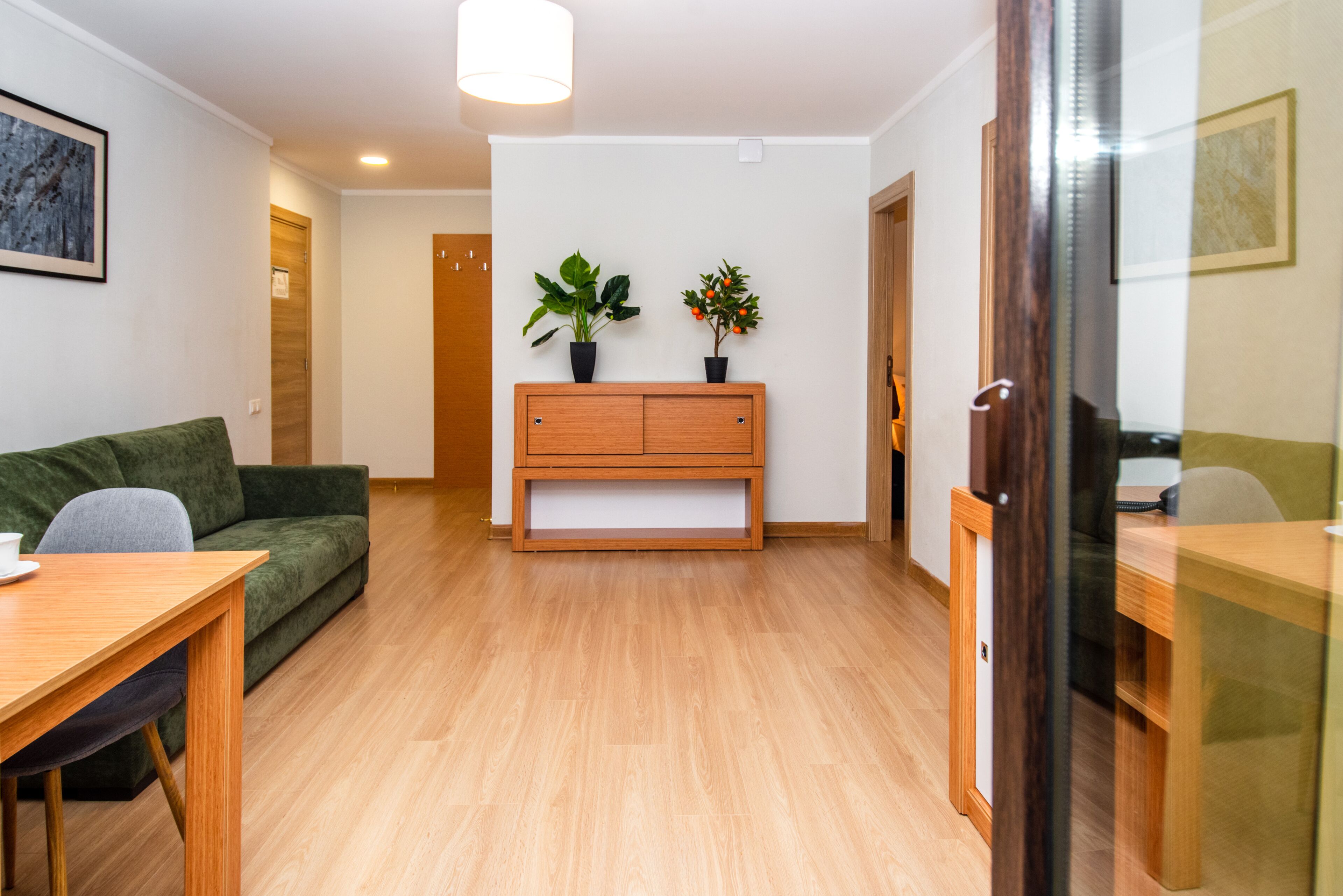 Un salon moderne avec un banc en bois, un canapé vert et une table à manger.