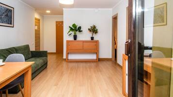 Un salon moderne avec un banc en bois, un canapé vert et une table à manger.