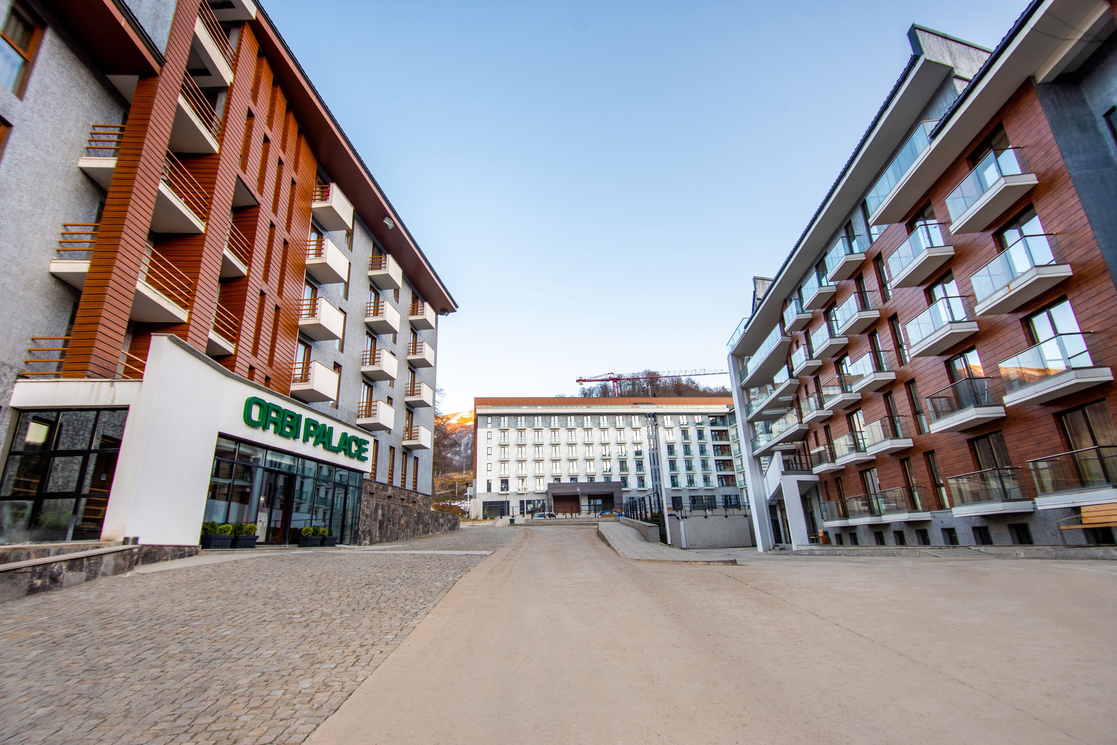 A modern hotel with a central entrance, multiple balconies, and a brick facade.