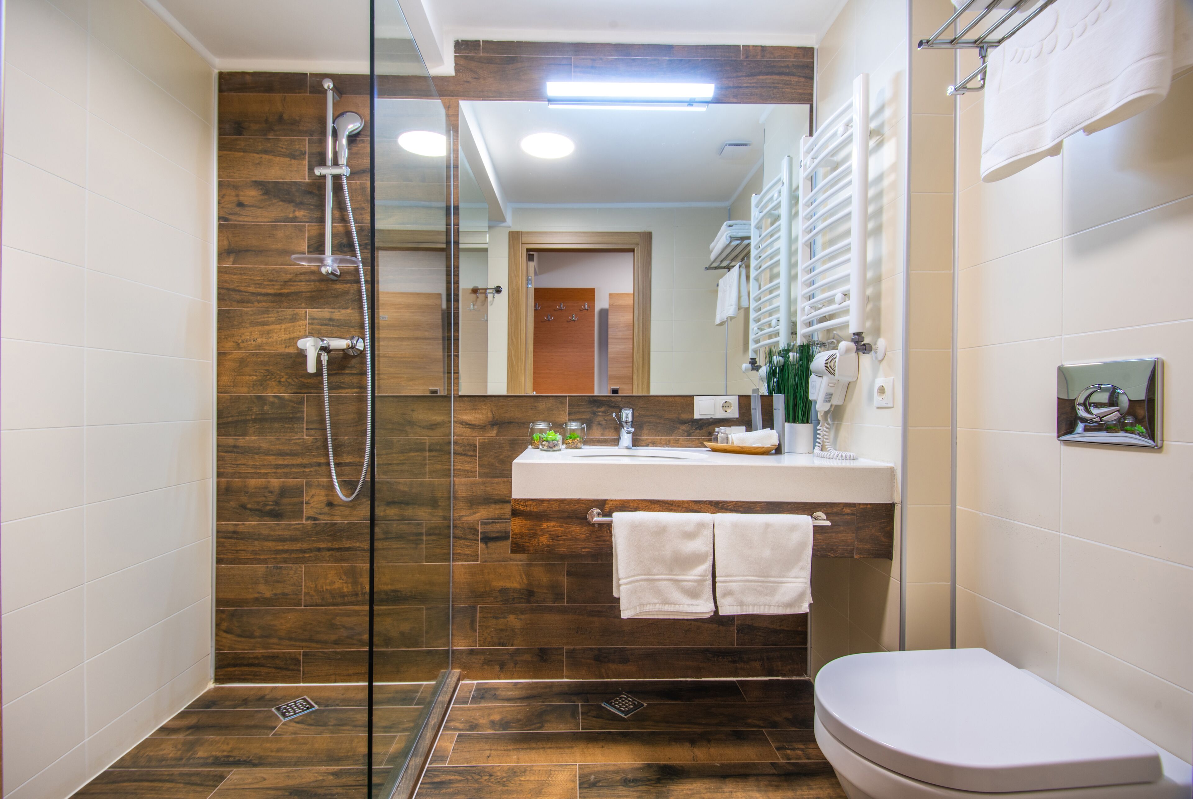 A modern bathroom with a glass-enclosed shower, a white sink with a mirror, and a toilet.