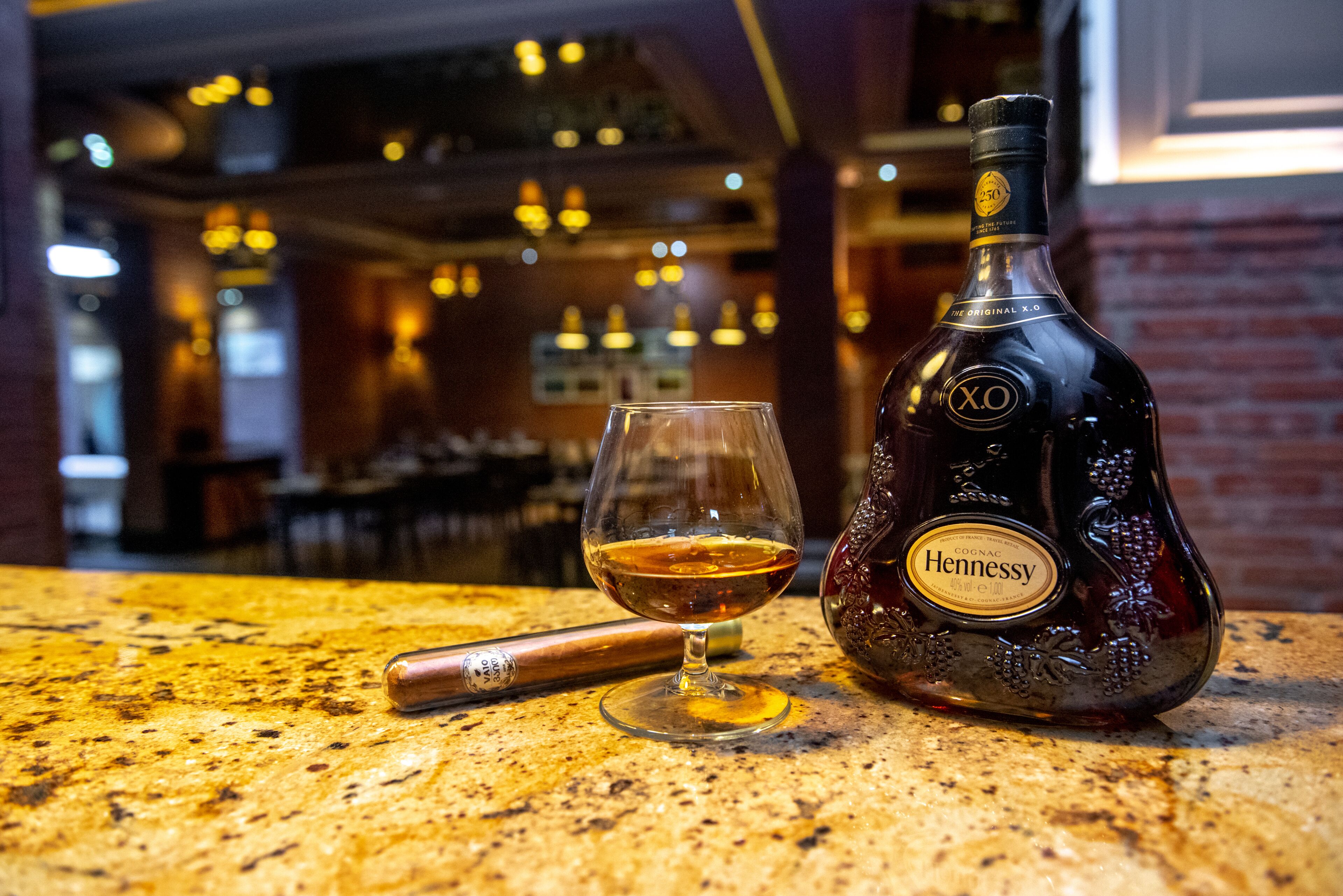 Eine Hennessy-Cognac-Flasche und ein Glas auf einer fleckigen Arbeitsplatte.
