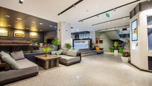 A modern reception area with a sofa, coffee table, and potted plants.