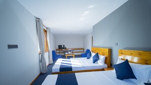 A hotel room with two beds, a desk, and a TV. - Havana Club Resort (Trincomalee)