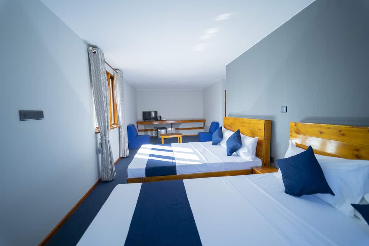 A hotel room with two beds, a desk, and a TV.