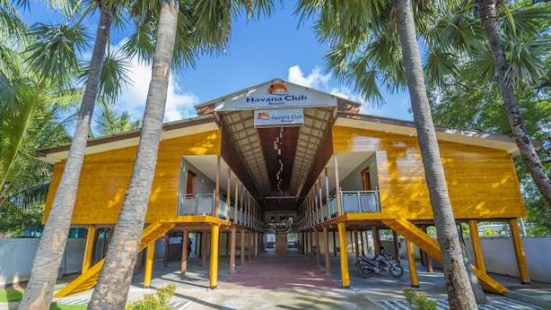 A resort with a central atrium, palm trees, and a clear sky. - Havana Club Resort (Trincomalee)