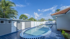 A swimming pool with a curved edge, surrounded by a white wall and a blue-tiled floor. - Havana Club Resort (Trincomalee)