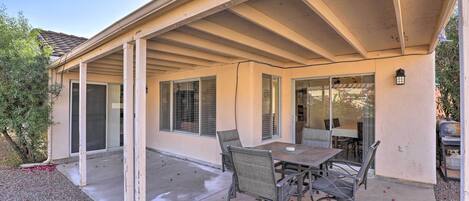 A covered patio with a table and chairs, a grill, and a sliding glass door.