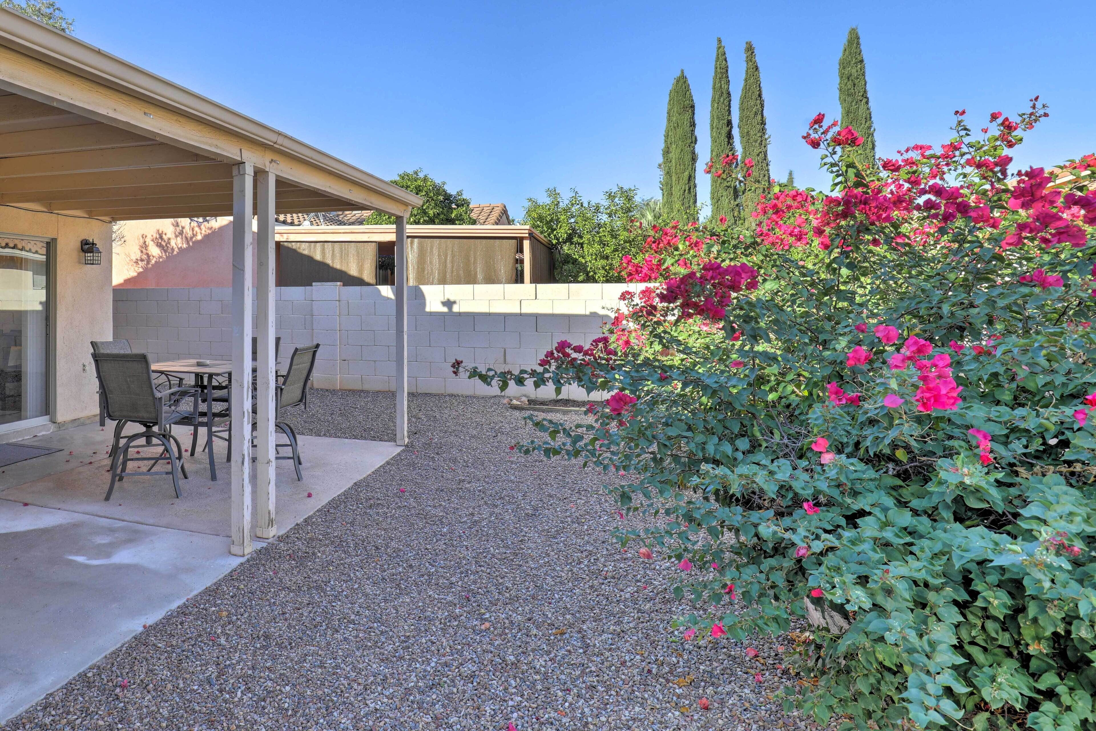 A covered patio area with a table and chairs, surrounded by a gravel floor and a brick wall.