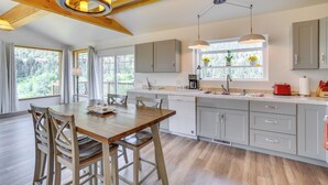 Una cucina moderna con travi in legno, mobili grigi e una zona pranzo con tavolo e sedie in legno.