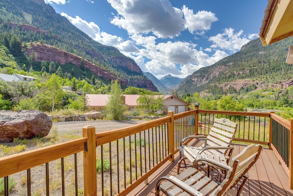 A wooden deck with chairs overlooking a mountainous landscape.