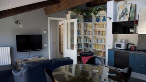 Ein modernes Wohnzimmer mit Glastisch, Ledersofa und einer Bücherwand voller Bücher.