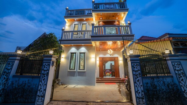 A two-story building with a balcony, a wooden door, and a small porch area. - Dream Countryside Villa (Siem Reap)