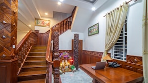 A wooden staircase with a decorative railing, a desk with a laptop, and a window with curtains. - Dream Countryside Villa (Siem Reap)
