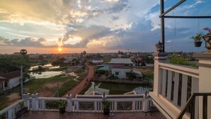 A balcony with a view of a village, a river, and a sunset. - Dream Countryside Villa (Siem Reap)
