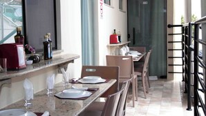 A restaurant with a long counter, chairs, and a window with a view. - Hotel Malbec (Aparecida)
