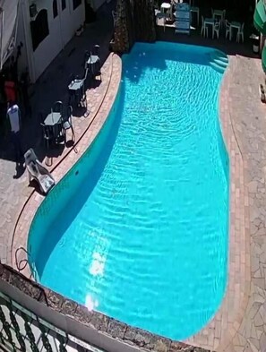 A swimming pool with a tiled deck and lounge chairs. - Hotel Malbec (Aparecida)