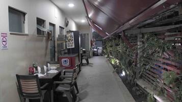 Un restaurante con una barra larga, sillas y un refrigerador. Hay un cartel que prohíbe fumar y una ventana pequeña en la pared.