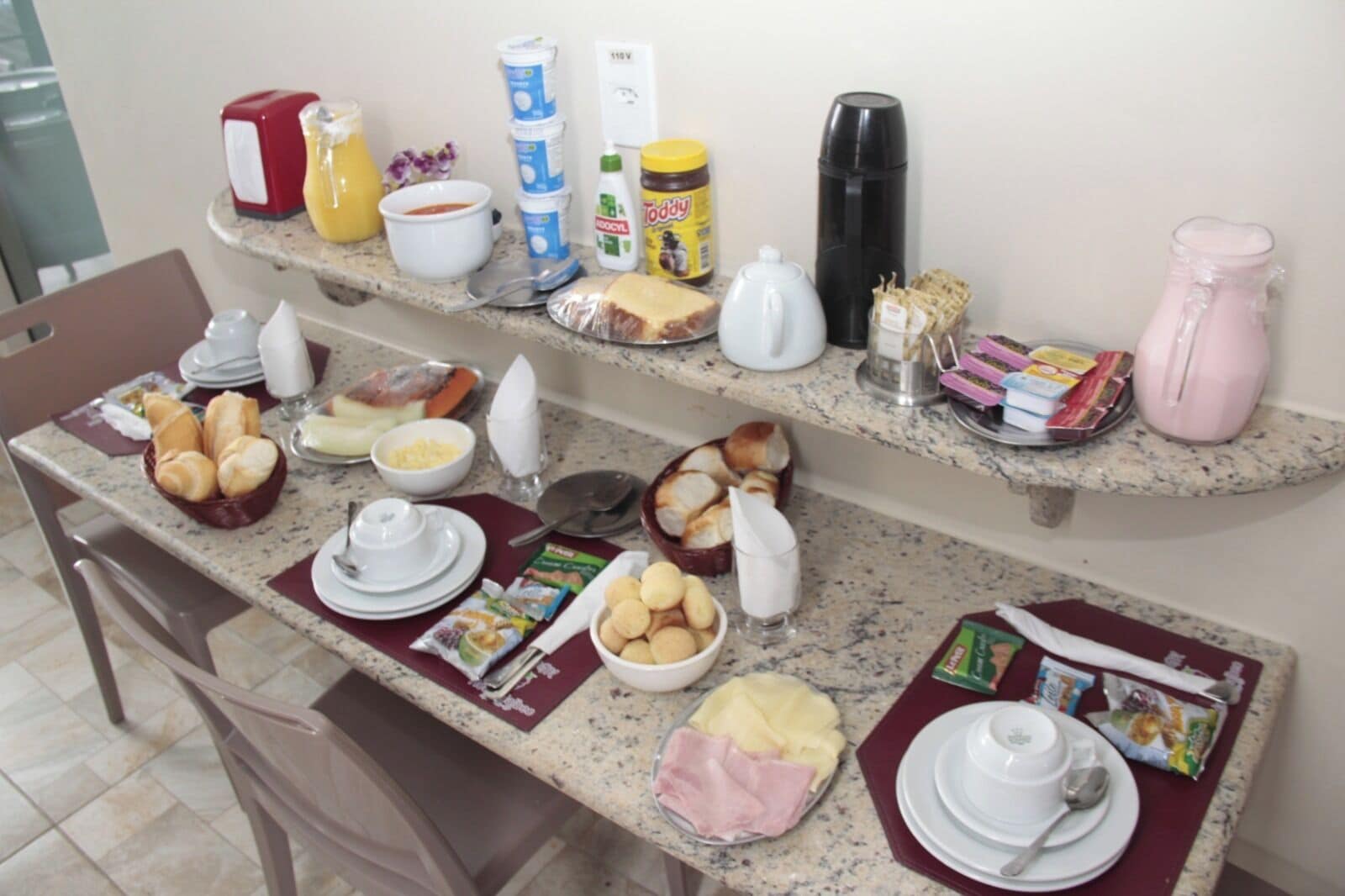 A breakfast buffet setup with various food items and condiments on two countertops.