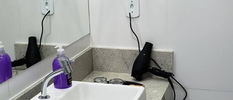 Une salle de bain avec un lavabo blanc, un miroir et un porte-serviettes.