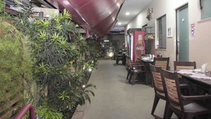 A restaurant with indoor plants, tables, chairs, and a Coca-Cola advertisement. - Hotel Malbec (Aparecida)
