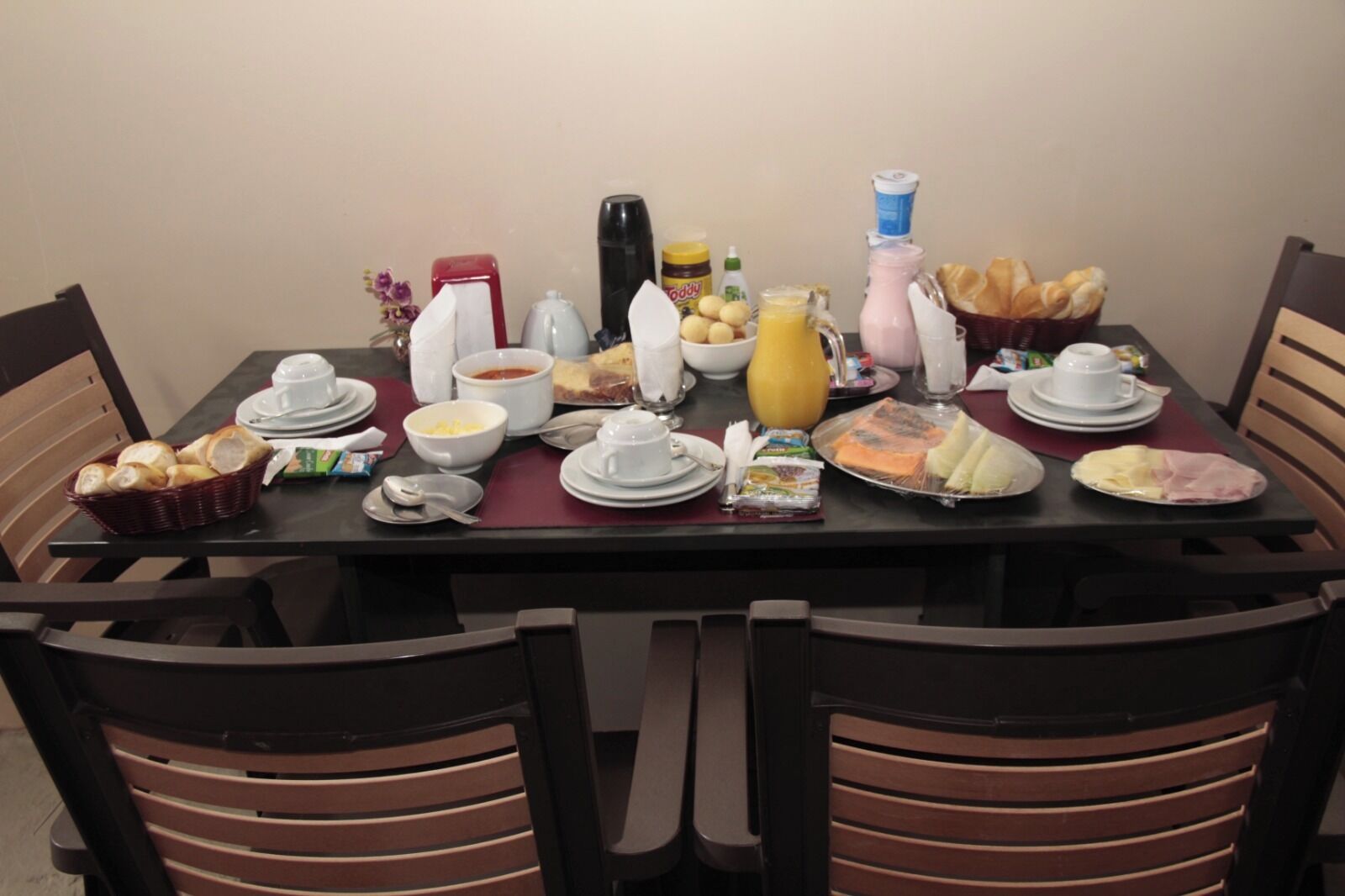 A dining table set with various breakfast items, including bread, eggs, and beverages.