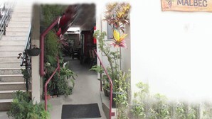 A hotel entrance with a staircase leading to a covered area, surrounded by potted plants and a sign reading "HOTEL MALBEC". - Hotel Malbec (Aparecida)