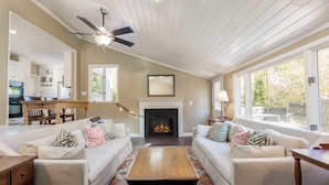 A living room with two sofas, a coffee table, a fireplace, and a ceiling fan. - In-Town Saugatuck  “Magical Backyard” with Fire Pit Walk to Town (Saugatuck)