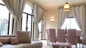 A modern living room with a beige sofa, pink chairs, and a glass coffee table. - Villa Mayrit. Beautiful Riyadh style villa in privileged surroundings (Marrakech)