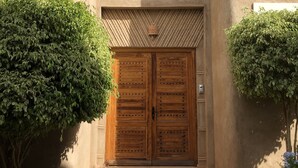 A building with a large wooden double door, a small balcony with three windows, and a textured facade. - Villa Mayrit. Beautiful Riyadh style villa in privileged surroundings (Marrakech)