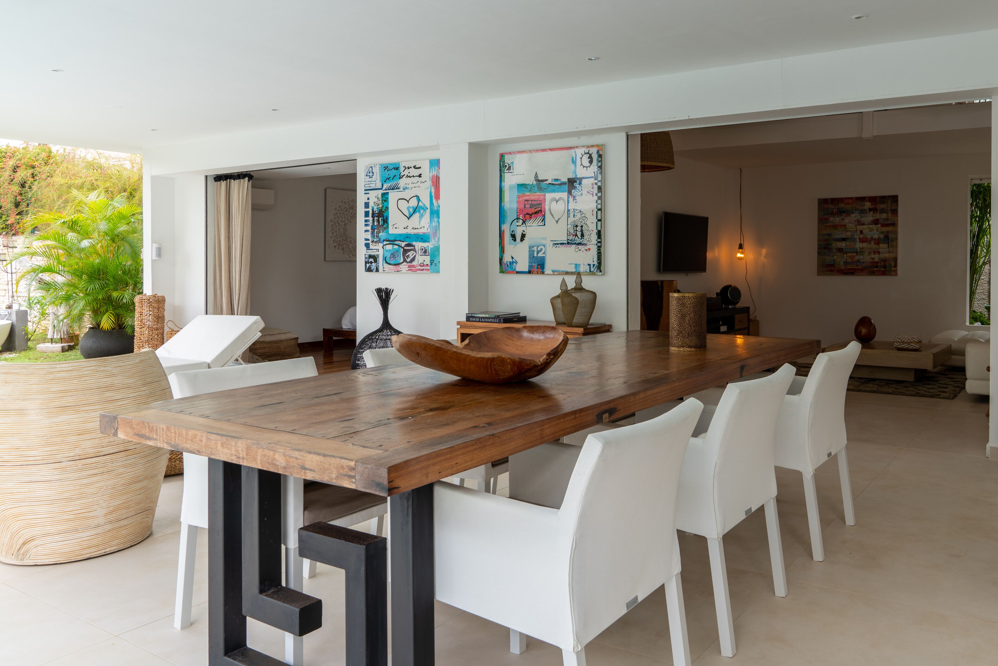 A modern dining area with a wooden table, white chairs, and a large decorative bowl.