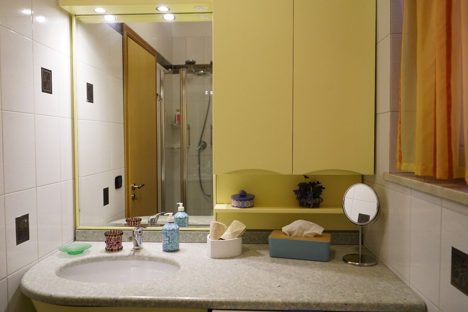 Un baño con lavabo, espejo y zona de ducha.