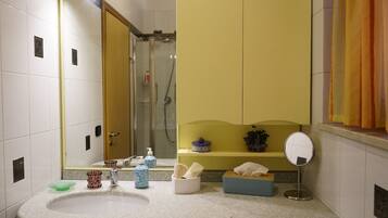 Un baño con lavabo, espejo y zona de ducha.