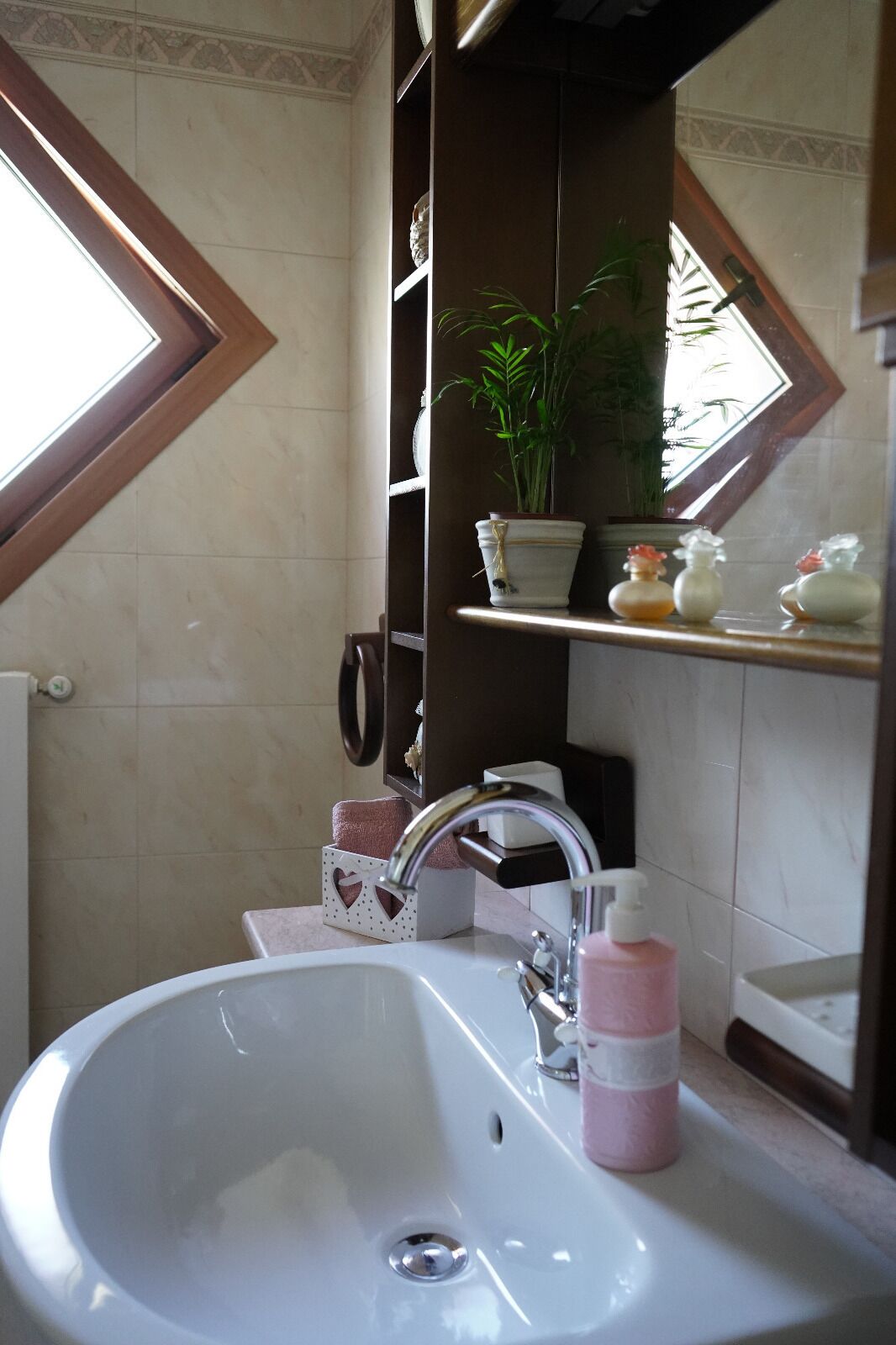 Une salle de bain avec un lavabo blanc, un miroir, un porte-serviettes et une étagère contenant des articles de toilette.