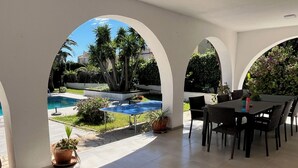 A covered patio area with a pool, outdoor seating, and potted plants. - villa with private pool, 11 people, air conditioning located 200m from the beach (L' Ametlla de Mar)