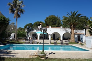 A pool area with lounge chairs and a building with arches in the background.