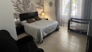 A bedroom with a bed, a nightstand, a lamp, a chair, and a window with curtains. - villa with private pool, 11 people, air conditioning located 200m from the beach (L' Ametlla de Mar)