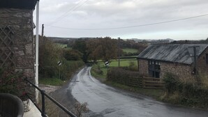 A rural road with stone buildings, a stone wall, and a fence. - The Huntsman Hotel (Chepstow)