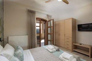 Ein Schlafzimmer mit Bett, Kleiderschrank, Fernseher und Blick durch eine Tür.