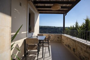Eine Terrasse im Freien mit Tisch und Stühlen, einer Pergola und Blick auf die Landschaft.