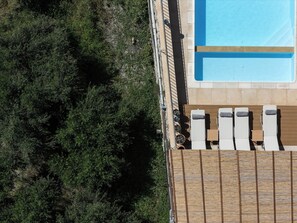 Zona de piscina amb gandules i un pont de fusta.