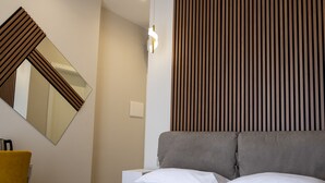 Une chambre d’hôtel avec un lit, une chaise, un miroir et un panneau mural.