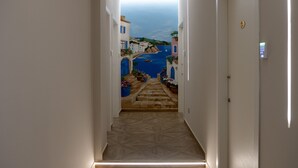 Un couloir donnant sur un paysage côtier, avec un plancher en bois et une porte dotée d’un clavier à code.