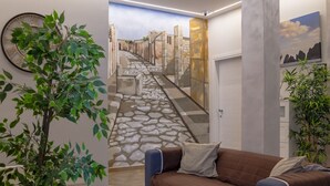 Un couloir avec un chemin en pierre, un canapé marron avec des coussins et une grande horloge murale.