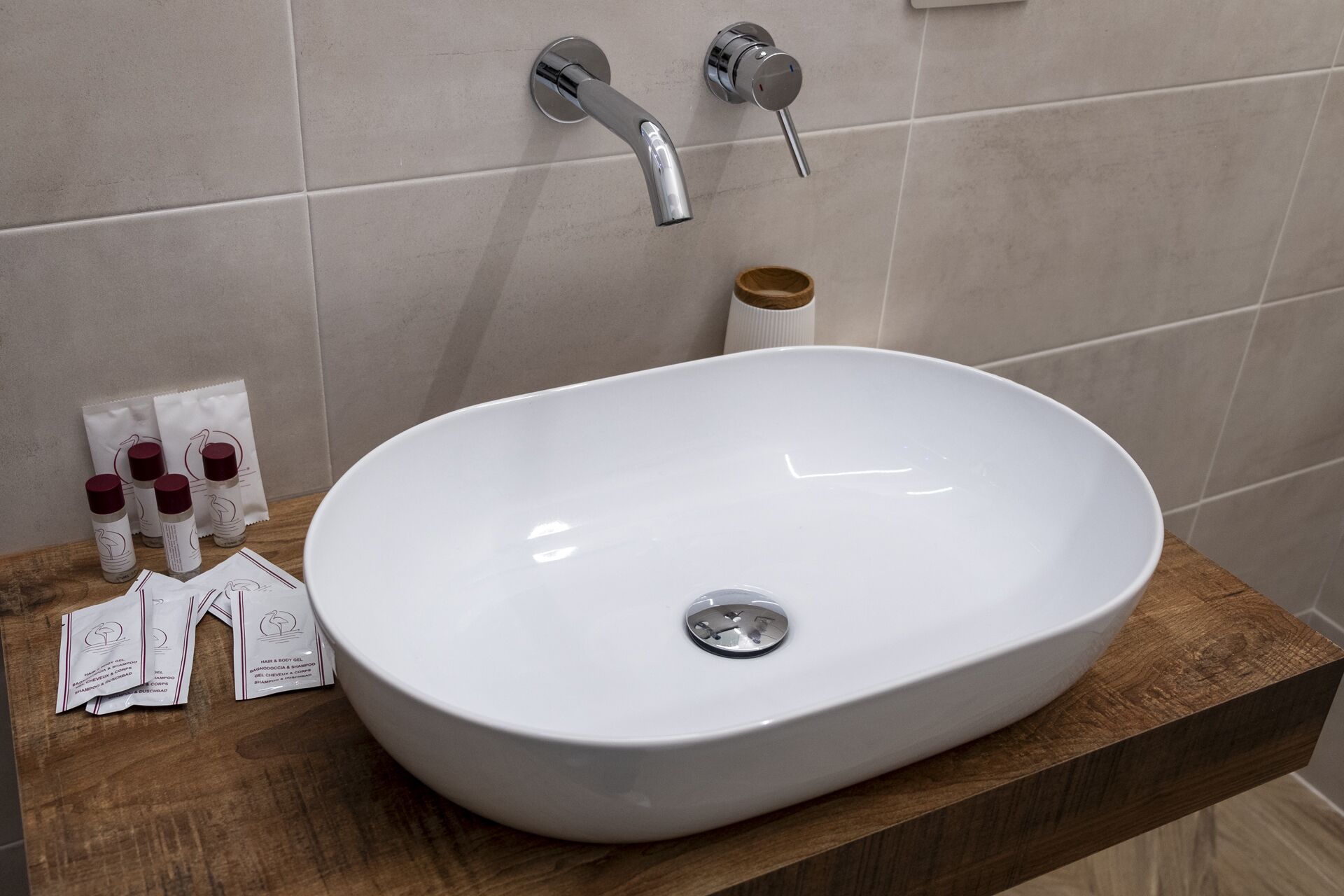 A bathroom with a white sink, a wooden countertop, and a mirror. There are toiletries on the counter.